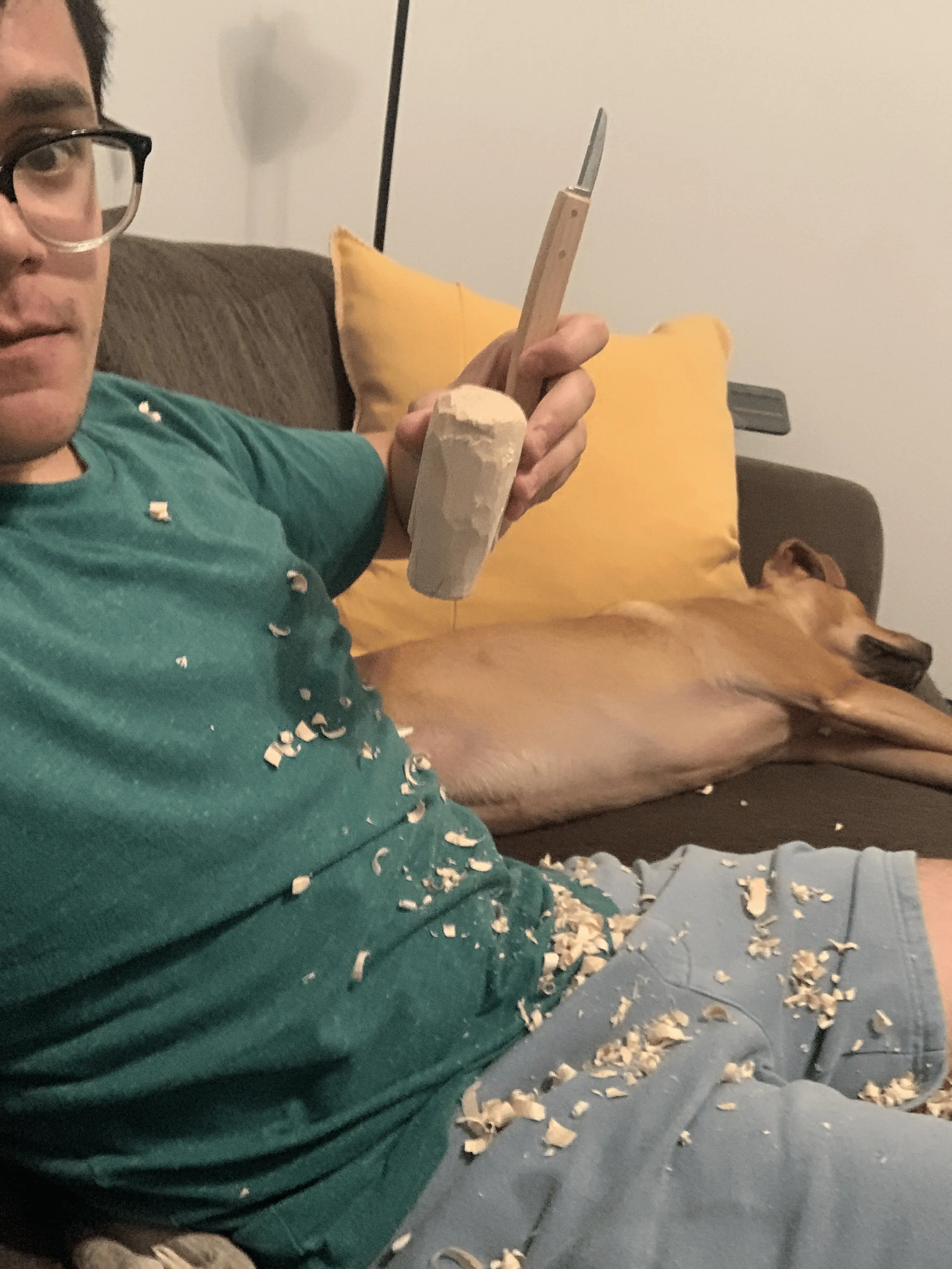 Holding up wood carving while covered in wood shavings